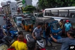 FILE - Sri Lankans wait in queue to buy petrol at a fuel station, in Colombo, Sri Lanka, July 17, 2022.