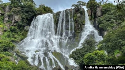 Visitors must jump between slippery rocks to reach the view from the top of Tabouna Falls in Guinea. It's the kind of tropical paradise that tourists would flock to, but its tourism sector has not yet been developed.