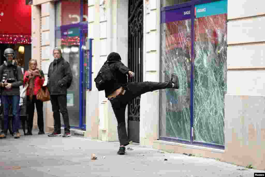 A demonstrator destroys a bank window in Paris during a nationwide day of strike and protests for higher wages and against requisitions at refineries in France.