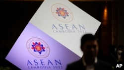 A man stand in front of the ASEAN logo at a hotel where the 55th ASEAN Foreign Ministers' Meeting (55th AMM) is taking place in Phnom Penh, Cambodia, Tuesday, Aug. 2, 2022. (AP Photo/Vincent Thian)