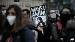 FILE - A woman shows a placard with a photo of of Iranian Mahsa Amini as she attends a protest against her death, in Berlin, Sept. 28, 2022. Amini's death in custody has sparked a stunning wave of protests across Iran.