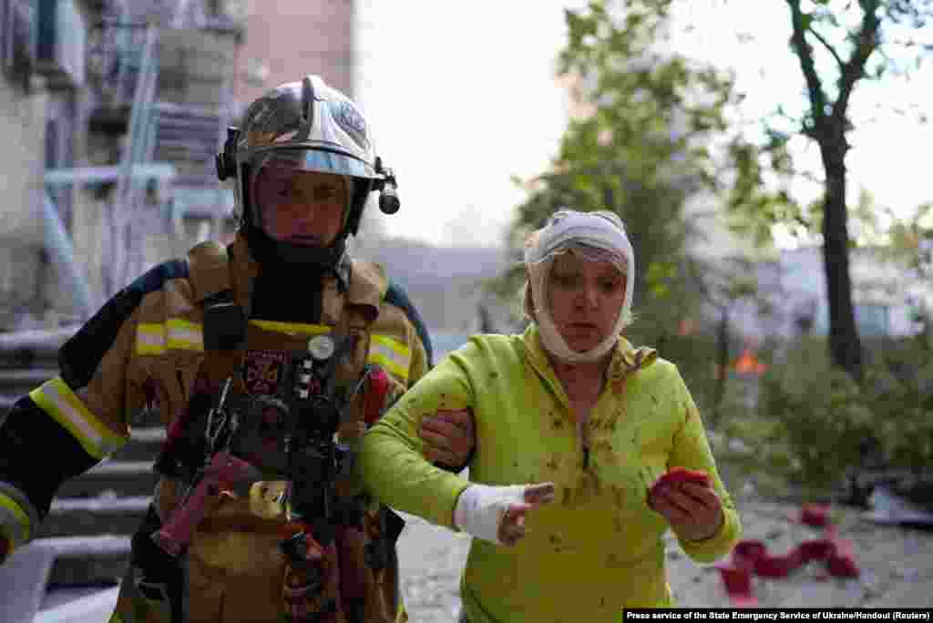 A rescuer helps an injured woman at a site of a building damaged by a Russian missile strike in Kyiv, Ukraine.&nbsp;At least 11 people were killed and 64 wounded in Russian missile strikes across&nbsp;Ukraine, the state emergency service said.