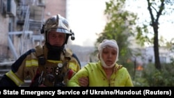 A rescuer helps an injured woman at the site of a building damaged by a Russian missile strike in Kyiv on October 10, 2022. (Press service of the State Emergency Service of Ukraine/via Reuters)