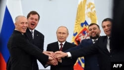 The Moscow-appointed heads of Ukraine's Kherson region and Donetsk and Lugansk separatist leaders join hands with Russian President Vladimir Putin (center) after signing treaties annexing four regions of Ukraine Russian troops occupy, in Moscow on Sept. 3