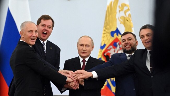 The Moscow-appointed heads of Ukraine's Kherson region and Donetsk and Lugansk separatist leaders join hands with Russian President Vladimir Putin (center) after signing treaties annexing four regions of Ukraine occupied by Russian troops, in Moscow on Sept. 30, 2022.