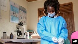 Medical lab assistant Mellon Kyomugisha, who said she was the first to examine the first confirmed Ebola victim when he came to St. Florence Clinic with malaria, takes a blood sample from a toddler at the clinic in Madudu, near Mubende, in Uganda, Sept. 28, 2022. 