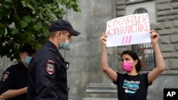 FILE - Police detain a journalist with a poster that reads "Journalism Freedom," in Moscow, Aug. 21, 2021. Russian police detained several journalists who protested authorities' decision to label a top independent TV channel as a "foreign agent."