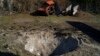 A destroyed car is seen next to a crater created by an explosion after a Russian attack in Zaporizhzhia, Ukraine, Oct. 15, 2022. 