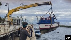 Trabajadores sacan un barco del agua en la bahía de La Habana, Cuba, el lunes 26 de septiembre de 2022. (AP Foto/Milexsy Duran)