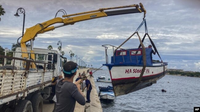 Trabajadores sacan un barco del agua en la bahía de La Habana, Cuba, el lunes 26 de septiembre de 2022. (AP Foto/Milexsy Duran)