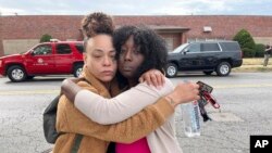 Janay Douglas, a la izquierda, y Renada Bridgett, a la derecha, en el exterior de Central Visual and Performing Arts High School en St. Louis, donde ocurrió el tiroteo el lunes 24 de octubre de 2022.