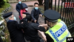 Aktivis prodemokrasi Hong Kong (tengah) tampak bergelut dengan staf Konsulat China di Manchester dalam aksi protes pada 16 Oktober 2022. (Foto: AFP/The Chaser News/Matthew Leung)