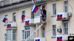 Punëtorët varin flamujt rusë në një ndërtesë apartamentesh në Luhansk, Ukrainë (27 shtator 2022)