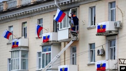 Punëtorët varin flamujt rusë në një ndërtesë apartamentesh në Luhansk, Ukrainë (27 shtator 2022)