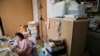FILE - Tokiko Onoda, who fled her home near the tsunami-crippled Fukushima nuclear plant, is seen in her cluttered apartment where she lives with her husband on the 21st floor of a high-rise on the edge of metropolitan Tokyo, Feb. 9, 2016.