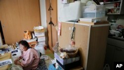 FILE - Tokiko Onoda, who fled her home near the tsunami-crippled Fukushima nuclear plant, is seen in her cluttered apartment where she lives with her husband on the 21st floor of a high-rise on the edge of metropolitan Tokyo, Feb. 9, 2016.