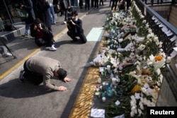 A man makes a deep bow while paying tribute near the site of a stampede that happened during Halloween festivities in Seoul, South Korea, Oct. 31, 2022.