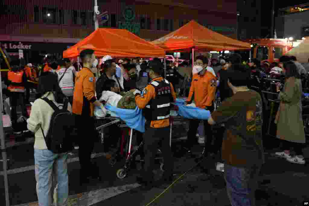 Rescue workers carry injured people in a street near the scene of a crush, in Seoul, South Korea, Oct. 30, 2022. 