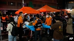 Rescue workers carry injured people in a street near the scene of a crush in Seoul, South Korea, Oct. 30, 2022. The surge that night left 159 dead.