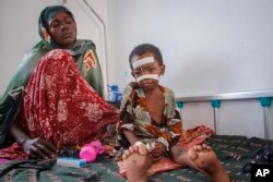 FILE - Malnourished Kalson Hussein, 4, sits next to her mother Isho Shukria, 35, at the Martini hospital where she is being treated in Mogadishu, Somalia, Sept. 3, 2022. Millions of people in the Horn of Africa region are going hungry because of drought, with Somalia especially hard hit because it sourced at least 90 percent of its grain from Ukraine and Russia before Russia invaded Ukraine.