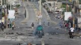 People pass through an empty street with remains of barricades during a nationwide strike against rising fuel prices, in Port-au-Prince, Haiti, Sept. 26, 2022. 