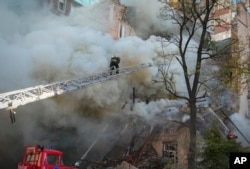 Firefighters work after a drone fired on buildings in Kyiv, Ukraine, Monday, Oct. 17, 2022. (AP Photo/Efrem Lukatsky)