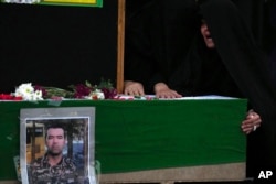 FILE - Wife of Hossein Taghipour cries over the flag-draped coffin of her husband, who was a member of Iranian paramilitary Basij force and was killed during recent anti-government protests over the death of Mahsa Amini, a 22-year-old woman who had been detained by the nation's morality police, in Tehran, Iran, Sept. 25, 2022.