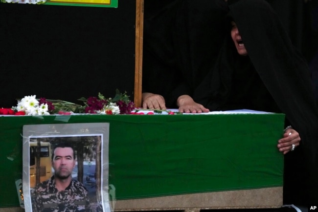 FILE - Wife of Hossein Taghipour cries over the flag-draped coffin of her husband, who was a member of Iranian paramilitary Basij force and was killed during recent anti-government protests over the death of Mahsa Amini, a 22-year-old woman who had been detained by the nation's morality police, in Tehran, Iran, Sept. 25, 2022.