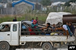 FILE - Displaced Syrians flee amid ongoing clashes between rival factions competing for power in northwest Syria, near the village of Jindayris in the Afrin region of Syria's rebel-held northern Aleppo province, Oct. 12, 2022.