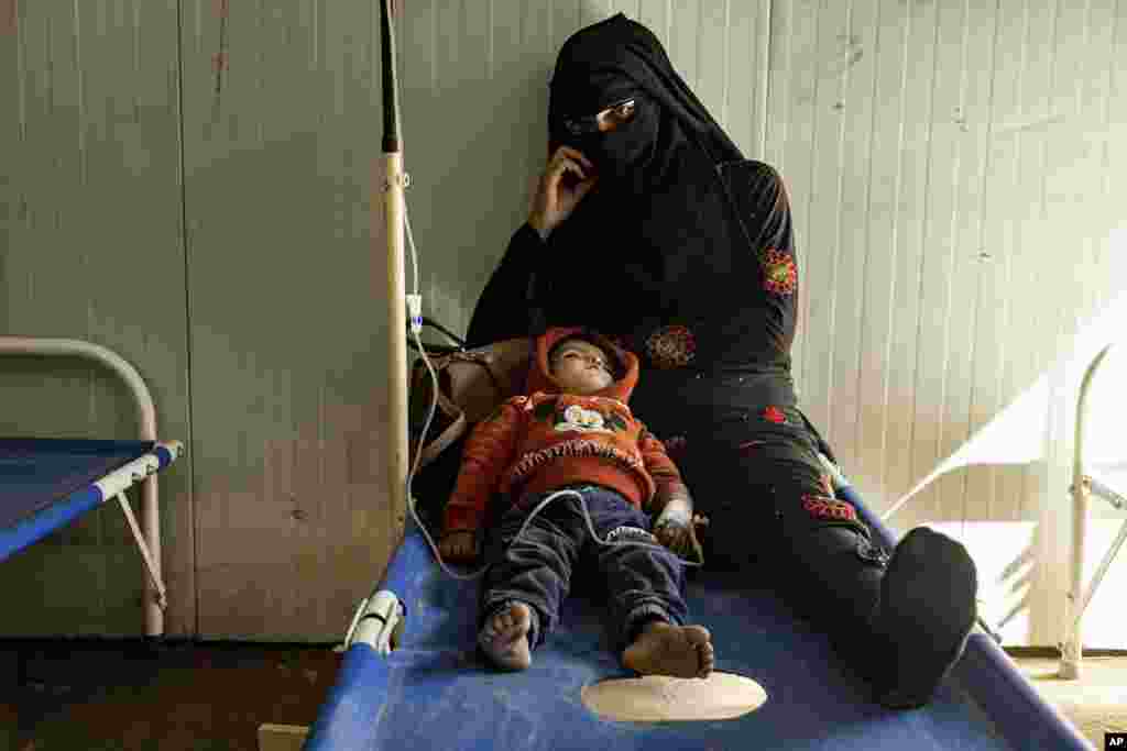 A mother sits with her child, who was diagnosed with cholera, at a hospital in Deir el-Zour, Syria.