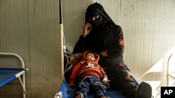 A mother sits with her child who was diagnosed with cholera in a hospital in Deir el-Zour, Syria, Sept. 29, 2022. 