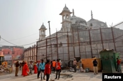 Buruh bekerja di kompleks kuil di sebelah pagar tembok Masjid Gyanvapi menjelang peresmian koridor baru Kuil Kashi Vishwanath oleh Perdana Menteri India Narendra Modi 12 Desember 2021. (Foto: REUTERS/Pawan Kumar)
