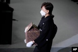Akie Abe, wife of former Prime Minister Shinzo Abe, carries a cinerary urn containing his ashes at his state funeral, Tuesday, Sept. 27, 2022, in Tokyo. Abe was assassinated in July. (Franck Robichon/Pool photo via AP)
