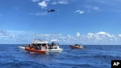 Esta imagen proporcionada por la Guardia Costera de EEUU muestra a los equipos de las fuerzas del orden público de la Guardia Costera ayudando a las personas desde un crucero de cabina de 40 pies sobrecargado a unas 20 millas de Boca Raton, Florida, el 12 de octubre de 2022. 