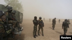 FILE - Cameroonian soldiers from the Rapid Intervention Brigade stand guard amidst dust kicked up by a helicopter in Kolofata, Cameroon, March 16, 2016. 