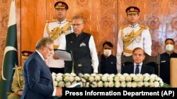 Presiden Pakistan Arif Alvi (tengah), mengambil sumpah jabatan Menteri Keuangan yang baru diangkat Ishaq Dar, (kiri), disaksikan Perdana Menteri Shehbaz Sharif (kanan), dalam upacara pelantikan di Islamabad, Pakistan, Rabu, 28 September.2022. (Pers Departemen Informasi vis AP)