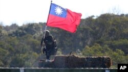 Seorang tentara memegang bendera Taiwan selama latihan militer yang bertujuan untuk menangkis serangan dari China di Hsinchu, Taiwan utara, sebagai ilustrasi. (Foto: AP)