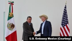 El embajador de EEUU ante México, Ken Salazar, (der) estrecha la mano del gobernador del estado mexicano de Zacatecas, David Monreal, (izq) el 6 de octubre de 2022.