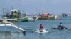 In this photo taken on August 20, 2022, crew on outriggers sail past fishing "mother" boats in the village of Cato, Infanta town, Pangasinan province, as they prepare to leave for a fishing expedition to the South China Sea.