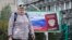 A woman walks past a billboard depicting Russian passport, a day after voting in four Moscow-held regions of Ukraine on referendums to become part of Russia, in Luhansk, Ukraine, Sept. 28, 2022.