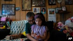 Alfred Ningeulook, 61, hugs his granddaughter, Glenna, 6, in his home in Shishmaref, Alaska, Sunday, Oct. 2, 2022. Rising sea levels, flooding, increased erosion and loss of protective sea ice and land have led residents of this island community to vote twice to relocate. 