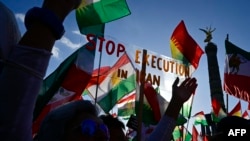 Para pengunjuk rasa memegang poster bertuliskan "Hentikan Eksekusi di Iran" dalam unjuk rasa mendukung demonstrasi di Iran, di depan Kolom Kemenangan di Berlin, 22 Oktober 2022. (Foto: John Macdougall/AFP)