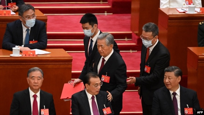 2022年10月22日，在北京人民大会堂举行的中共二十大闭幕式上，习近平看着前中共总书记胡锦涛被警卫扶着离席时拍了一下中国总理李克强的臂膀。