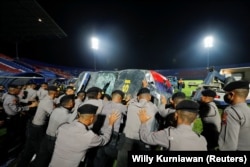 Aparat kepolisian mendorong kendaraan yang rusak saat akan memindahkannya keluar dari Stadion Kanjuruhan, tempat terjadi kerusuhan dan kericuhan usai pertandingan sepak bola antara Arema vs Persebaya, di Malang, Jawa Timur, 2 Oktober 2022. (Foto: REUTERS)