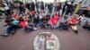 Protesters sit on the street outside City Hall during the Los Angeles City Council meeting in Los Angeles, Oct. 11, 2022. 