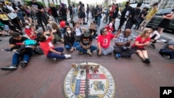 Protesters sit on the street outside City Hall during the Los Angeles City Council meeting in Los Angeles, Oct. 11, 2022. 