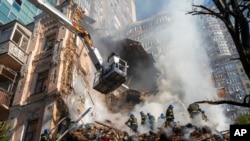 Petugas pemadam kebakaran berusaha memadamkan kobaran api setelah serangan drone Rusia menghancurkan gedung-gedung di Kyiv, Ukraina, 17 Oktober 2022.