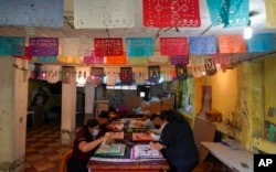 Artisans make “papel picado,” the traditional manufacture of tissue paper cutout decorations long used in altars for the Day of the Dead, in a workshop in Xochimilco, a borough of Mexico City, Oct. 27, 2022.