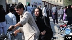 A woman arrives on a motorbike to search for a relative at a hospital in Kabul on Sept. 30, 2022, after a blast in a learning center in the Dasht-e-Barchi area of Afghanistan's capital.