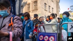 Visitors wearing face masks show their results on a health check smartphone app to guards as they enter a tourist shopping street in Beijing, Oct. 7, 2022.